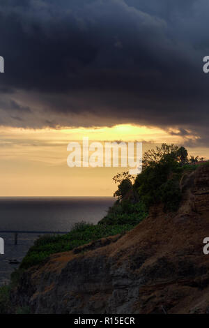 Dunkle Wolken über felsige Küste bei Sonnenuntergang. Portugiesische Insel Madeira Stockfoto