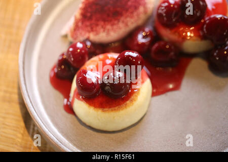 Makro Foto von leckeren hellen Käse Kuchen mit Kirsche Konfitüre und Sauerrahm auf einer Platte Stockfoto