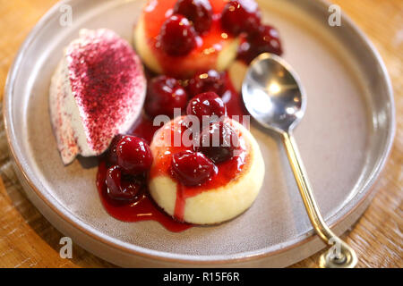 Makro Foto von leckeren hellen Käse Kuchen mit Kirsche Konfitüre und Sauerrahm auf einer Platte Stockfoto