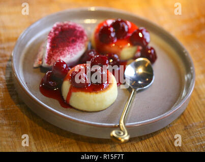 Makro Foto von leckeren hellen Käse Kuchen mit Kirsche Konfitüre und Sauerrahm auf einer Platte Stockfoto