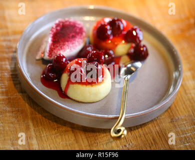 Makro Foto von leckeren hellen Käse Kuchen mit Kirsche Konfitüre und Sauerrahm auf einer Platte Stockfoto