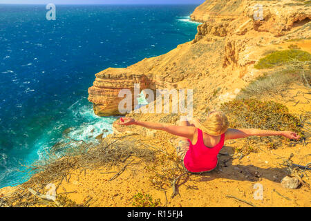 Glückliche Frau mit offenen Armen auf natürliche Brücke in Kalbarri Nationalpark, Western Australia. Backpacker Mädchen auf Klippen der Küste des Indischen Ozeans. Australische Outback reisen. Blauer Himmel, Sommer sonnigen Tag. Stockfoto