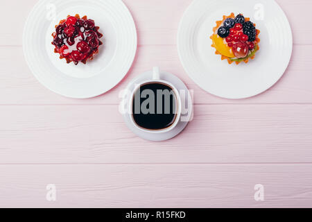 Zusammensetzung der leckere kleine Kuchen mit Espresso auf rosa Holz- Tabelle, Ansicht von oben. Flach Anordnung von schwarzen Kaffee und Desserts mit kopieren. Stockfoto