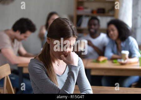 Vielfältigen, multi-ethnischen Freunde sitzen zusammen im Café sprechen, Spaß haben, den Schwerpunkt auf die frustrierten schüchterne Mädchen getrennt sitzen, die durch andere Jugendliche fühlt sich un Stockfoto