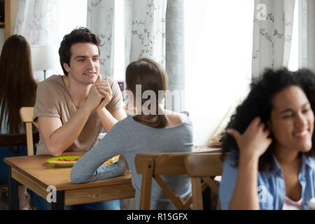 Diverse Schüler junge Leute sitzen in der Zeile in der Nähe der Fenster sprechen Zeit mit soulmates oder mit Freunden in der gemütlichen Cafeteria während der Mittagspause, Fokus auf cauc Stockfoto