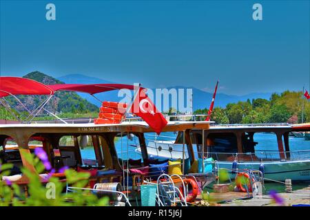 Dalyan, Türkei - 7. Juli 2018: Pkw Boote auf dem Fluss Cayi mit Blick auf die Berge im Hintergrund. Stockfoto