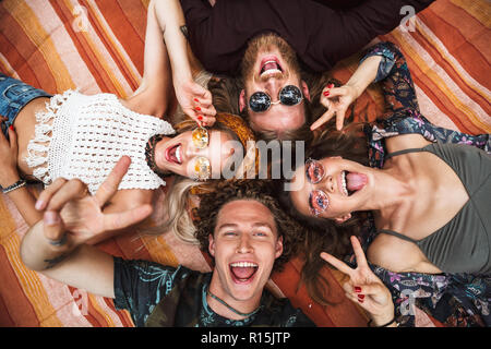 Porträt der schönen Hippies Freunde Jungs und Mädchen lachen und liegen auf Decke im Kreis outdoor Stockfoto