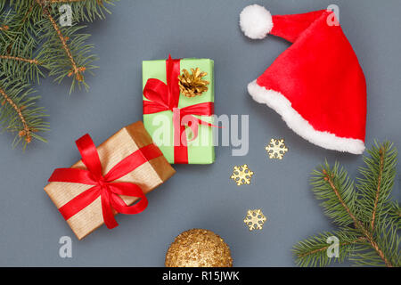 Weihnachtsdekoration. Geschenkboxen, Santa's Hut, Spielzeug, Ball, dekorative Schneeflocken und natürlichen Tannenbaum Äste auf grauem Hintergrund. Ansicht von oben. Weihnachten g Stockfoto