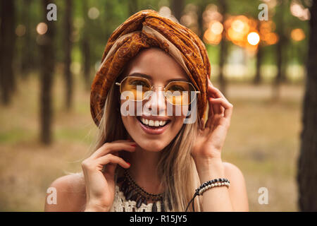 Foto von Happy Hippy Frau mit stilvollen Accessoires, Lächeln beim Laufen im Wald Stockfoto