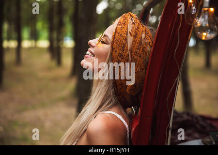 Foto der Europäischen hippie Frau mit stilvollen Accessoires zur Seite schauen, während in Forest Camp ruhen Stockfoto