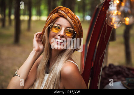 Foto des Blonden cute woman tragen stilvolle Accessoires lächelnd während in Forest Camp ruhen Stockfoto