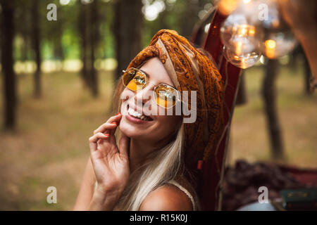 Foto der Freude und nette Frau mit stilvollen Accessoires, lächelnd, während in Forest Camp ruhen Stockfoto