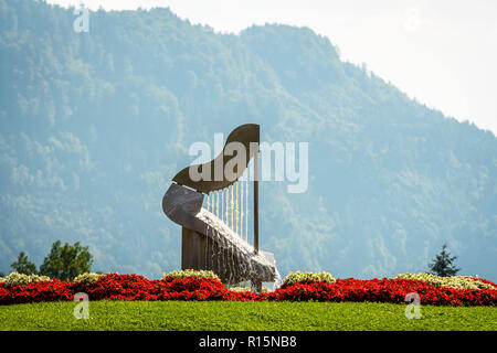 Die Harfe Brunnen in Fulpmes, Österreich. Wald und Berge im Hintergrund. Stockfoto