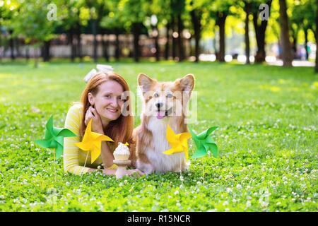Hund in der Familie - Geburtstag aus schönen Corgi flauschige auf grünem Rasen und bunte party Flaggen auf dem Hintergrund Stockfoto