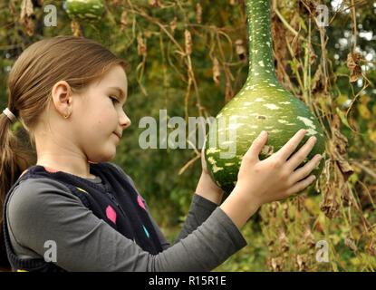 Kaukasische 8 Jahre alten Kind, Mädchen, glücklich, im Park, auf der Suche bei einer großen Flasche Kürbis Stockfoto