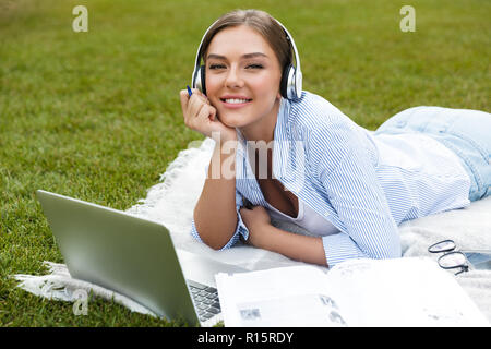 Glückliche junge Mädchen in Kopfhörer Zeit im Park, studieren, Festlegung auf eine Decke mit Laptop Stockfoto