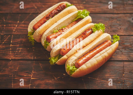 Leckere amerikanische Hot Dogs sortiert in Reihe. Auf hölzernen Tisch gelegt. Oben Ansicht auf einem rustikalen, mit Holz Hintergrund Stockfoto