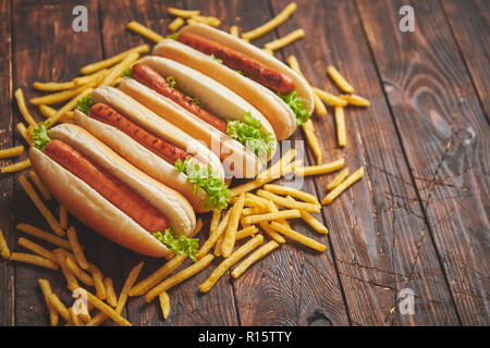 American Hot Dogs sortiert in Reihe. Mit Pommes frites serviert. Auf hölzernen Tisch gelegt. Oben Ansicht auf einem rustikalen, mit Holz Hintergrund Stockfoto