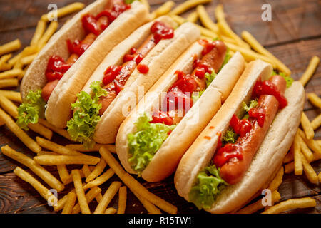 American Hot Dogs sortiert in Reihe. Mit Pommes frites serviert. Auf hölzernen Tisch gelegt. Oben Ansicht auf einem rustikalen, mit Holz Hintergrund Stockfoto