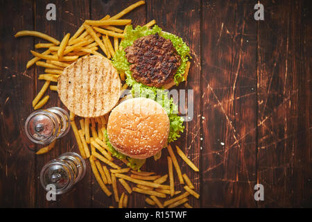 Amerikanische Klassiker. Zwei leckere gegrillte hausgemachte Burger mit Rindfleisch, Salat und französischen frides an der Seite. Ansicht von oben mit der Kopie Raum Stockfoto