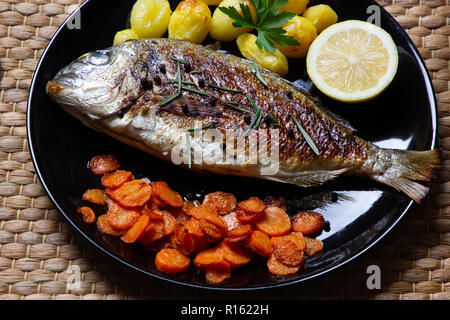 Eine vorzüglich gesunde Mahlzeit: Dorade, sautierten Karotten und gebackene Kartoffeln Stockfoto