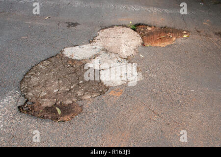 Eine Nahaufnahme von Reparaturen, die auf die volle und Abdeckung nach oben getan haben eine riesige Pole Bohrung in der tar-Straße Stockfoto