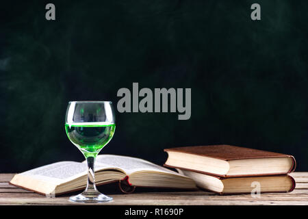 Absinth oder Grüne Fee trinken Inspiration und Muse der Schriftsteller und Künstler. Glas auf retro Holztisch und Bücher. Grüne verrauchten dunklen Hintergrund Stockfoto