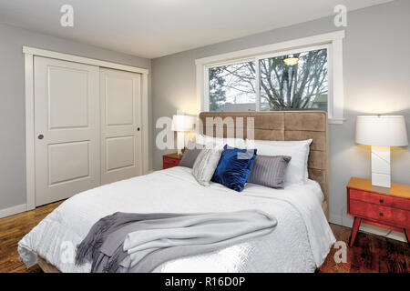 Grau Schlafzimmer Innenraum mit einem riesigen Bett, getuftet Kopfteil und Hartholzboden. Stockfoto
