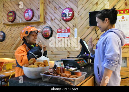 (181109) - jinan, November 9, 2018 (Xinhua) - Hörgeschädigte Lieferung rider Gao Li (L) nimmt einen Lieferauftrag in Kuiwen Bezirk Weifang, Provinz Shandong im Osten Chinas, November 8, 2018. Eine ausgelagerte Instant Delivery Service Provider in Weifang ist es gelungen, mehr als 30 hörgeschädigte Reiter, die nach relevanten beruflichen Schulungen, bewähren sich genauso kompetent wie ihre Altersgenossen ohne Hörverlust zu beschäftigen. Der hörgeschädigten Delivery Team besteht aus Fahrern aus unterschiedlichen Hintergründen: Hochschulabsolvent, alleinerziehende Mutter, ehemaliger fahren Bus und andere. Und die Palette Stockfoto