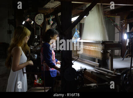 Hanoi, Vietnam. 8 Nov, 2018. Ein Besucher Uhren eine handwerkerin bei Van Phuc Seide Dorf in Hanoi, Vietnam, Nov. 8, 2018. Van Phuc ist eine der bekanntesten und ältesten Seide - Weberei Dorf in Vietnam. Ihre Produkte sind nicht nur vielfältig in Vietnam verzehrt, aber auch in vielen anderen Ländern und Regionen in der ganzen Welt exportiert. Credit: Ngo Minh Tien/Xinhua/Alamy leben Nachrichten Stockfoto