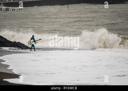 Aberystwyth Wales UK, 10/11/2018.de Wetter: Eine wilde, nassen und stürmischen Morgen in Aberystwyth, mit riesigen Wellen bei Flut entlang der Promenade und Meer Verteidigung der Küstenstadt auf die Cardigan Bay, West Wales. Lokale pro Surfer LEIGH DENYER macht den meisten starker Dünung und fängt den Wellen. Foto Keith Morris/Alamy leben Nachrichten Stockfoto