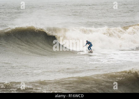 Aberystwyth Wales UK, 10/11/2018.de Wetter: Eine wilde, nassen und stürmischen Morgen in Aberystwyth, mit riesigen Wellen bei Flut entlang der Promenade und Meer Verteidigung der Küstenstadt auf die Cardigan Bay, West Wales. Lokale pro Surfer LEIGH DENYER macht den meisten starker Dünung und fängt den Wellen. Foto Keith Morris/Alamy leben Nachrichten Stockfoto