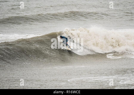 Aberystwyth Wales UK, 10/11/2018.de Wetter: Eine wilde, nassen und stürmischen Morgen in Aberystwyth, mit riesigen Wellen bei Flut entlang der Promenade und Meer Verteidigung der Küstenstadt auf die Cardigan Bay, West Wales. Lokale pro Surfer LEIGH DENYER macht den meisten starker Dünung und fängt den Wellen. Foto Keith Morris/Alamy leben Nachrichten Stockfoto