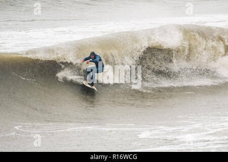 Aberystwyth Wales UK, 10/11/2018.de Wetter: Eine wilde, nassen und stürmischen Morgen in Aberystwyth, mit riesigen Wellen bei Flut entlang der Promenade und Meer Verteidigung der Küstenstadt auf die Cardigan Bay, West Wales. Lokale pro Surfer LEIGH DENYER macht den meisten starker Dünung und fängt den Wellen. Foto Keith Morris/Alamy leben Nachrichten Stockfoto