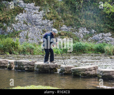 Ältere Dame Wanderer überqueren Trittsteine in der Derbyshire Peak District Dovedale. England Ugold Stockfoto