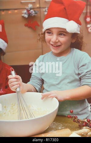 Little Boy, Weihnachtsplätzchen, Portrait eines Santa Helfer tragen rot festlich hat und hausgemachte Lebkuchen Stockfoto