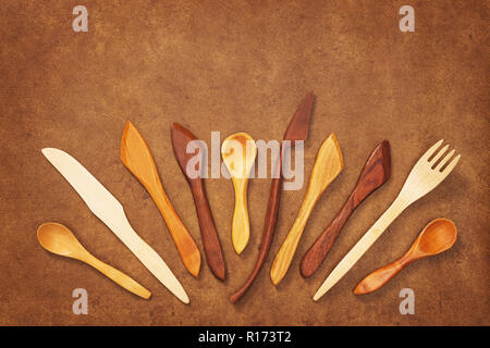 Handgefertigten Holz- Utensilien auf braunem Hintergrund. Gabel, Löffel und Messer. Stockfoto