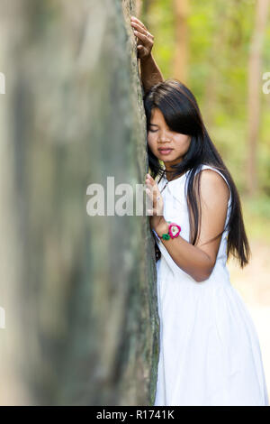 Junge Thai Girl Holding auf einem großen Granitfelsen mit geschlossenen Augen und einem heiteren Ausdruck, als sie meditiert und genießt die Ruhe und den Frieden o Stockfoto