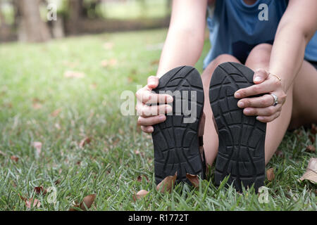 Hand der Frau, die ihre Füße halten und die Muskeln in den Park. Stockfoto