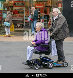 Ältere Paare, auf modifizierte Batterie powered mobility Scooter mit einem Anhänger mit zwei Menschen in Blackpool, Großbritannien angepasst Stockfoto