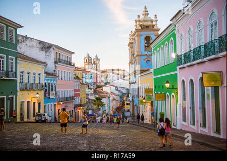 SALVADOR, BRASILIEN - ca. März 2018: Touristen nehmen Bilder der bunten kolonialen Architektur entlang der gepflasterten Hügel von Pelourinho. Stockfoto