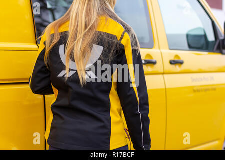 BERLIN/Deutschland - NOVEMBER 9,2018: Weibliche postboten der Deutschen Post und DHL auf Yellow postcar. Stockfoto