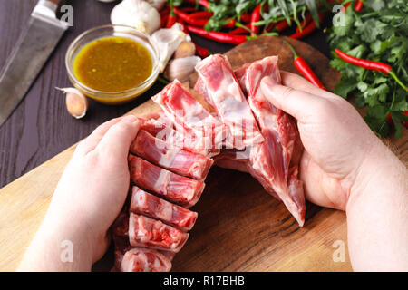 Die starke professionelle man Hände schneiden rohes Lammfleisch, selektiver Fokus, Nahaufnahme Stockfoto