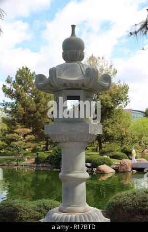 Eine japanische Stein Laterne vor einem künstlichen See in einem japanischen Garten. Stockfoto