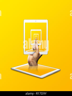 Person, die digitale Tablet mit sich wiederholenden Bild vor gelbem Hintergrund Stockfoto
