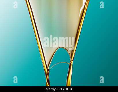 Golden gefärbten Öl fließt in V-Form vor blauem Hintergrund Stockfoto