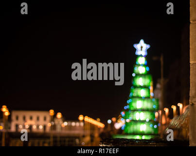 Eine unfokussierte Weihnachten Hintergrund mit bunten Lichter am Weihnachtsbaum, mit dem Brunnen von Pelayo auf den ersten Begriff. Gijon, Spanien, Europa Stockfoto