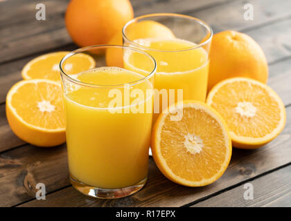 Zwei Gläser Orangensaft mit Orangen auf hölzernen Tisch Stockfoto