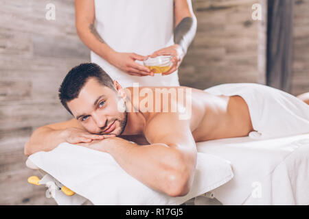 Schöne perlen Mann liegen auf Massage Tisch in Spa Salon Stockfoto