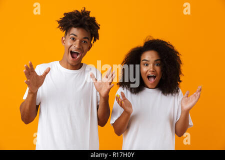 Bild von Angeregten emotionale Junge niedlichen afrikanischen Paar über gelben Hintergrund posiert. Stockfoto